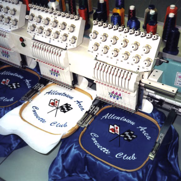 Embroidery machine showing the Allentown Area Corvette Club logo being stitched on satin jackets